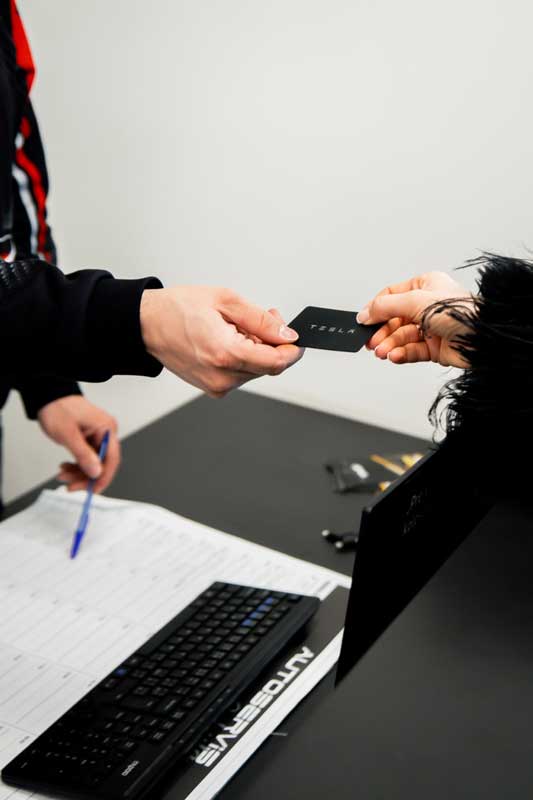 Klient odovzdáva kľúč od Automobilu Tesla technikovi.