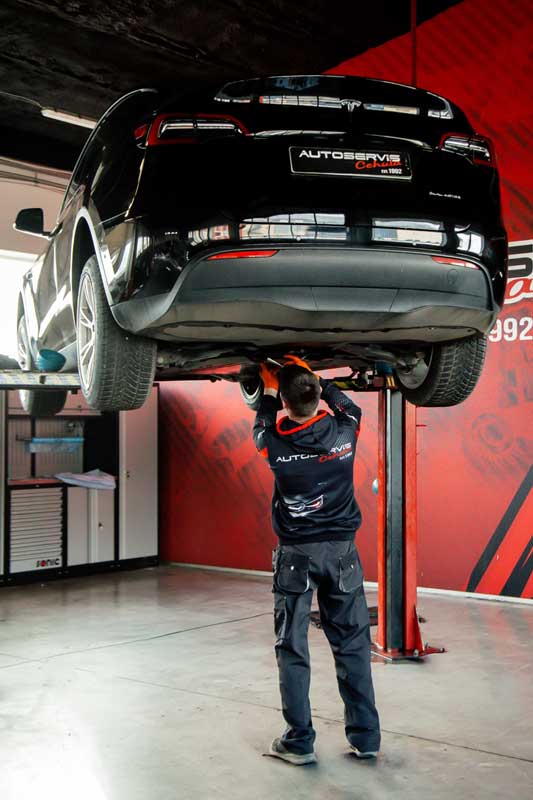 Technik opravuje podvozok automibilu Tesla v servise Cehula Poprad.